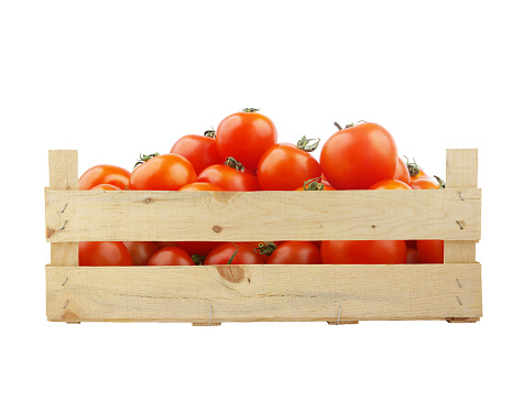 Fresh tomatoes in a box. On a wooden table.