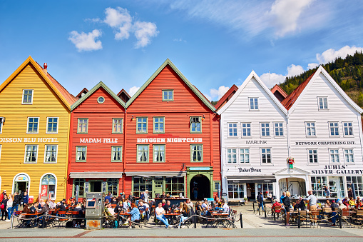 Bergen, Norway - May 02, 2022: Bryggen street with old traditional wooden hanseatic commercial buildings, cafe, shops