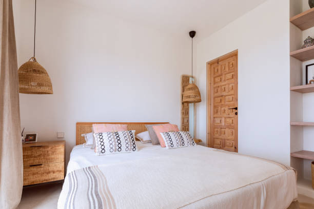 habitación de invitados de villa mediterránea con candelabros de mimbre, cama doble con ropa de cama de estilo local y puerta de madera con incrustaciones - huésped fotografías e imágenes de stock