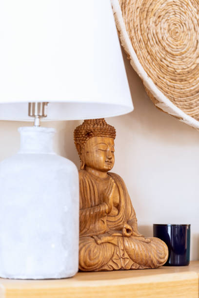 istock Decorative interior elements in ethnic style with white table lamp, wooden statue of Buddha and wicker wall planter (Vertical shot) 1402439203