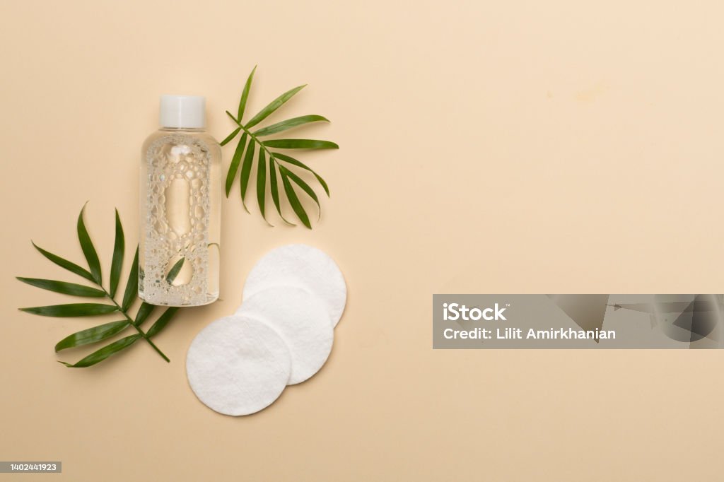 Micellar cleansing water and cotton pads on color background, top view Micellar cleansing water and cotton pads on color background, top view. Facial Cleanser Stock Photo