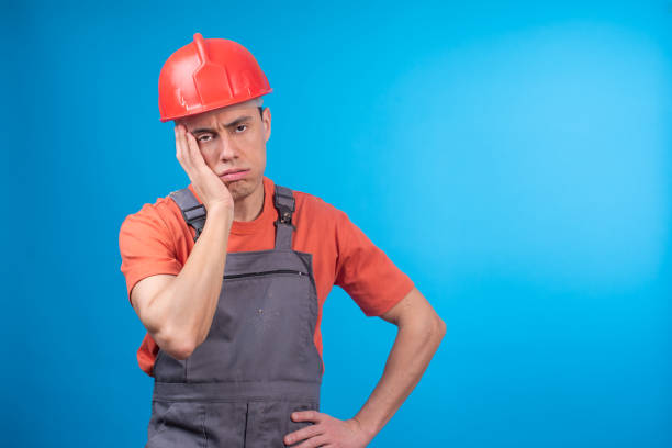 istock Weary male contractor in uniform touching face 1402443060