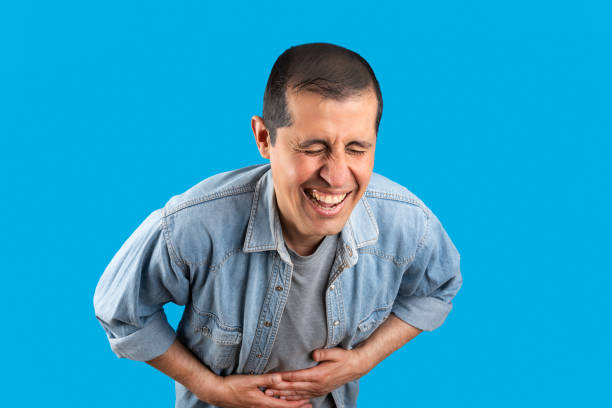 happy man man bursting out laughing over blue background Studio shot of a handsome elegant man over isolated blue background smiling and laughing hard out loud because funny crazy joke. Happy expression man laughing hard stock pictures, royalty-free photos & images