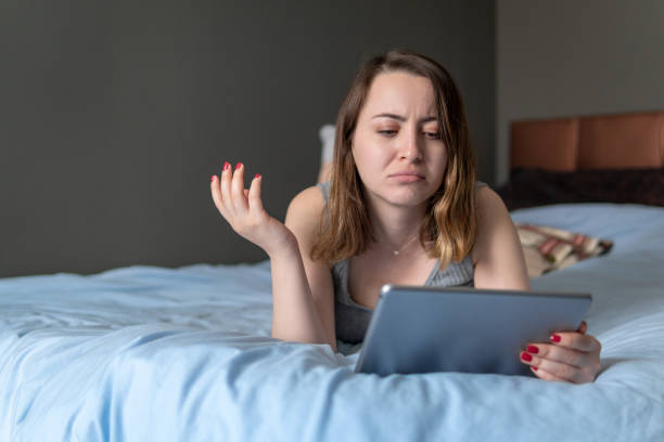 giovane donna scioccata che guarda lo schermo del tablet digitale che riceve cattive notizie - teenager laptop computer anger foto e immagini stock