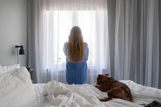 istock Woman looking out through the bedroom window 1402450021
