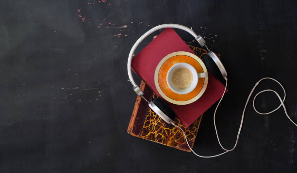 audio book with stack of books, cup of espresso coffee and headphones flat lay, good copy space. stock photo
