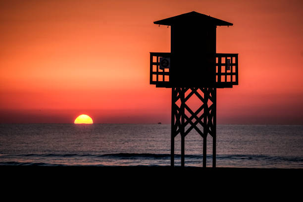 Red sunset on the beach with a lifeguard watchtower