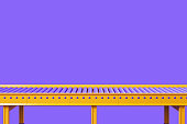 Empty yellow conveyor on violet background, assembly line, copy space
