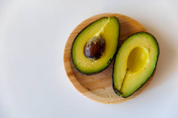 istock Avocado on an ecological wooden plate with a white background close-up 1402462947