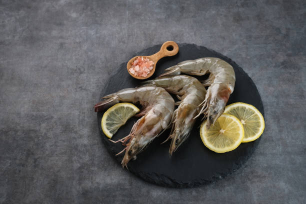 Fresh shrimps served on plate with dark background.