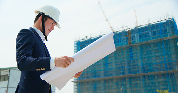 Professional architect contractor or Worker Wearing suit and Hard Hat looking at technical drawing on construction site