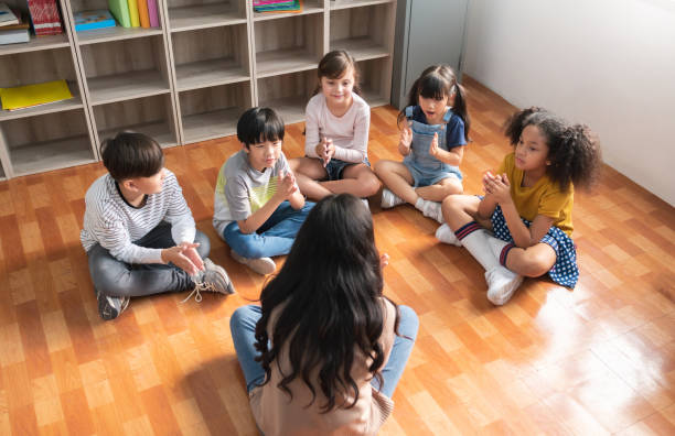 maestra asiática y grupo de alumnos de escuela primaria multiétnica cantando juntas - asiático de asia sudoriental fotografías e imágenes de stock