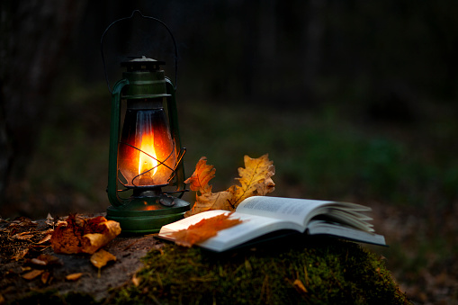 An open book in the light of a lantern in autumn