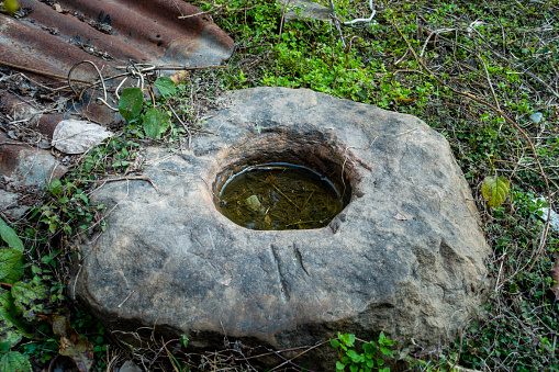 A close up shot of a round pothole on a stone filled with rain water. Uttarakhand India.