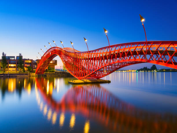 un pont dans la ville la nuit. le pont sur fond de ciel bleu pendant l’heure bleue. architecture et design. le pont python, amsterdam, pays-bas. - python photos et images de collection