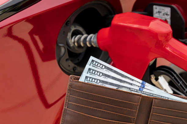 Fueling car at gas station with cash money in wallet. Gas price increase, tax and fuel shortage concept. stock photo