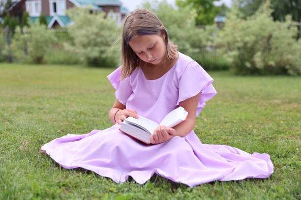 Cute little girl reading book outdoors. Summertime rest