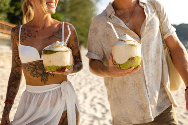 istock Unrecognizable Caucasian couple walking on the beach and drinking coconut 1402475706