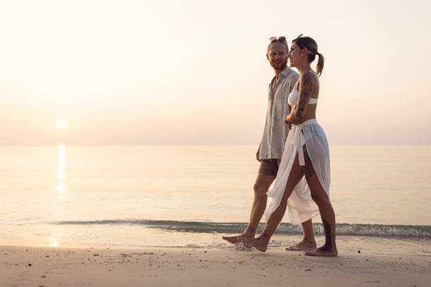 istock Caucasian couple holding hands while walking on the beach during sunset 1402475743