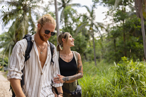 Young Caucasian couple holding hands while exploring the rainforest