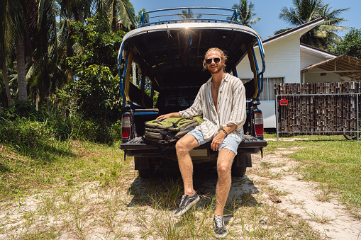 Portrait of young Caucasian male tourist, sitting on the off road taxi trunk