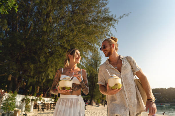 istock Caucasian couple walking on the beach and drinking coconut on the beach 1402476590