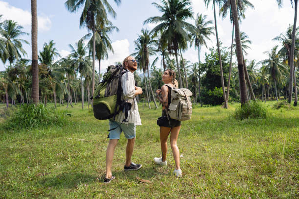 Rear-view of adventurous couple exploring the rainforest Rear-view of young Caucasian couple holding hands while exploring the rainforest body adornment rear view young men men stock pictures, royalty-free photos & images