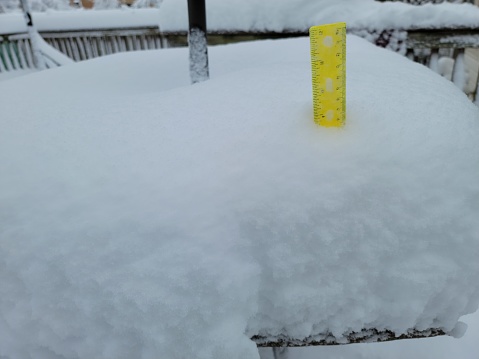 deep snow pile on table in winter with yellow ruler to measure