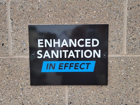 enhanced sanitation in effect sign on grey brick wall