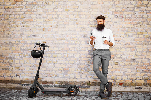Bearded Businessman Going To Work By Electric Scooter