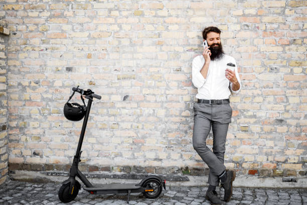 istock Bearded Businessman Going To Work By Electric Scooter talking on smart phone 1402479677