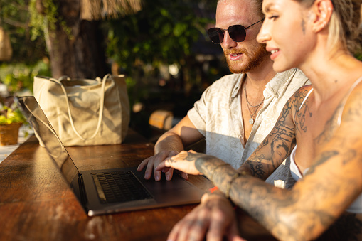 Modern young Caucasian couple working on laptop from coffee shop, on their vacation at Thailand