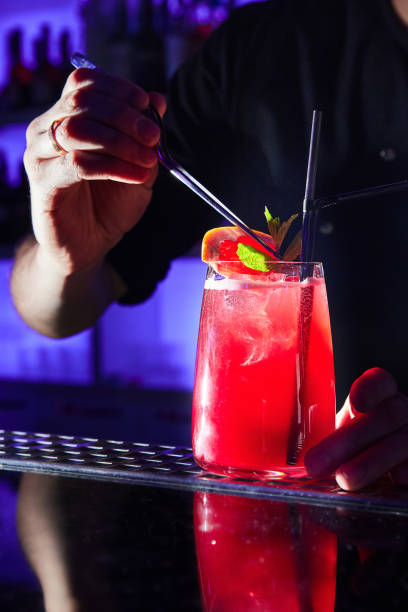 istock Bartender decorates red alcoholic cocktail with mint leaves 1402480523