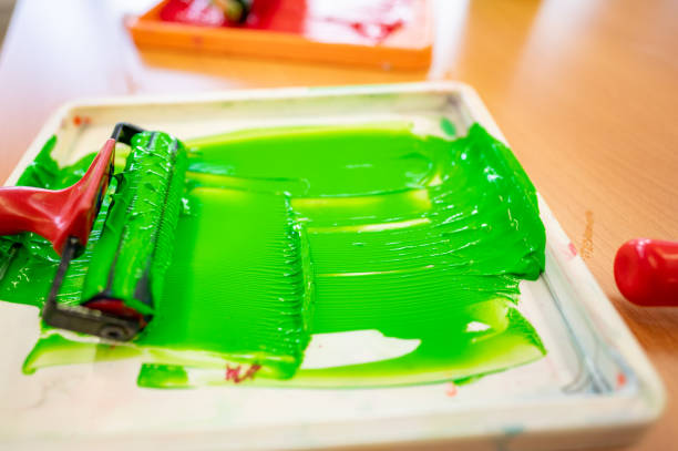 Roll of green paint prepared in a tray in a worker's hand before painting