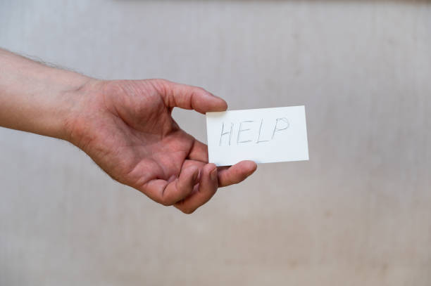 istock Help. The word is written in uneven letters. A man's hand holds a white paper rectangle with text against a gray background. 1402481095