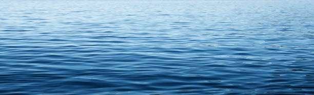 Calm Blue Waters Of A Large Body Of Water The calm waves on the surface of a large body of water such as a lake or the ocean. calm water stock pictures, royalty-free photos & images