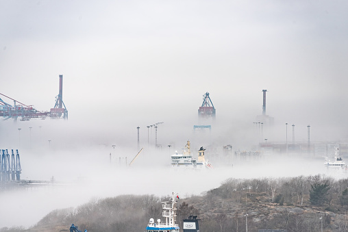 Gothenborg, Sweden - April 14 2022: Container cranes at Skandiahamnen in dense local fog.