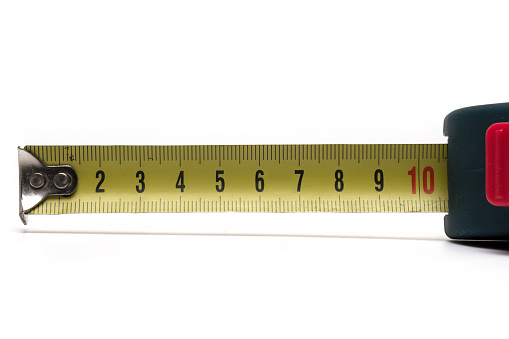 Close up of blue roll meter tape measure with yellow dimension track black numbers digits and red button on white background as concept for precision an measurement