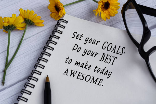 Motivational quote on note book with sunflowers on wooden desk. stock photo