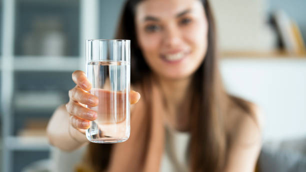 Young woman drinks a glass of water stock photo