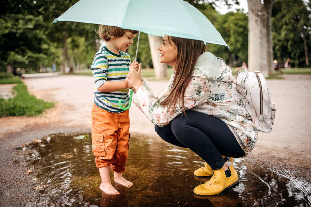 We love puddles Happy family playing in the street after a rain. raining outside stock pictures, royalty-free photos & images
