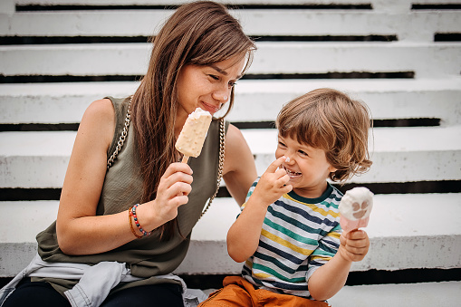 Mother and son having fun in public park, eating ice cream