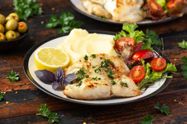 istock Fried cod loin fillet with mashed potato and vegetable salad served with fresh lemon 1402496923