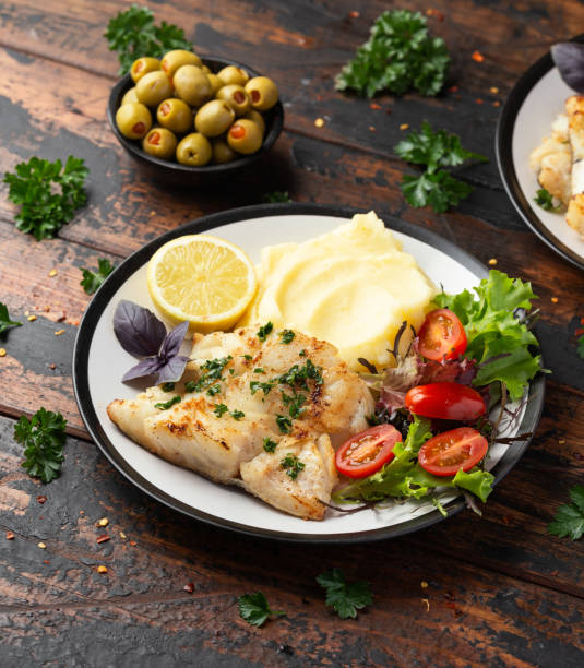 istock Fried cod loin fillet with mashed potato and vegetable salad served with fresh lemon 1402496934