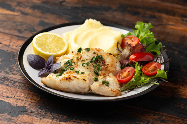 istock Fried cod loin fillet with mashed potato and vegetable salad served with fresh lemon 1402496944