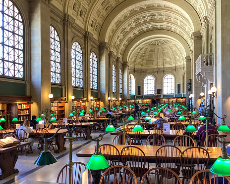 Boston, Massachusetts, USA - May 18, 2022: People are learning, studying and reading books in Bates Hall at The Boston Public Library. The Boston Public Library contains approximately 24 million items, making it the third-largest public library in the United States behind the federal Library of Congress and the New York Public Library.
