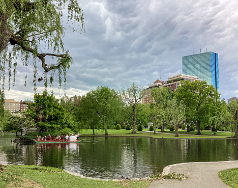 Boston, Massachusetts, USA - May 17, 2022: Swan Boats reflecting on a small pond in the Boston Public Garden during the spring season