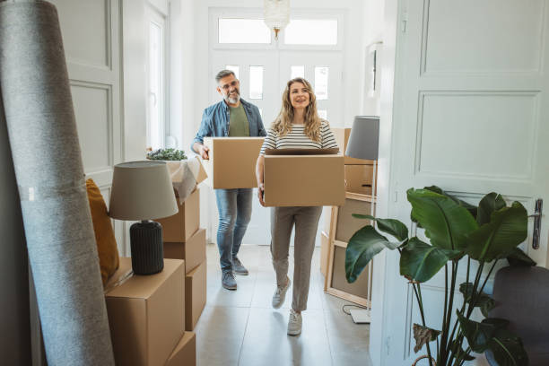 Mature Couple with Moving Boxes in New Home Mature couple moves in to their new home, unpacking boxes and enjoying the time together. mover stock pictures, royalty-free photos & images