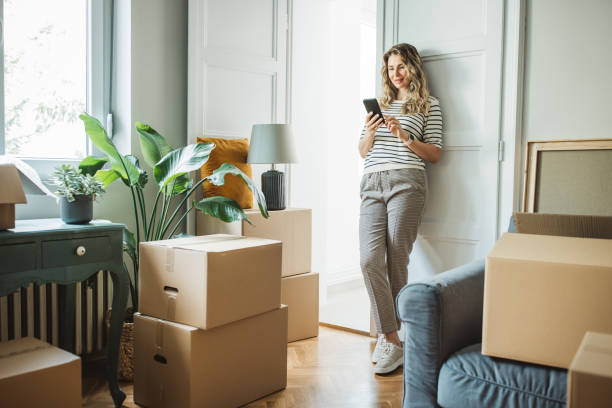 mujer madura con cajas de mudanza en un nuevo hogar - wireless technology fotos fotografías e imágenes de stock