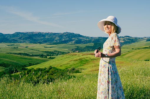 Mature woman on vacation enjoying the view of the wine country near the village of Volterra in the Tuscany region of Italy.